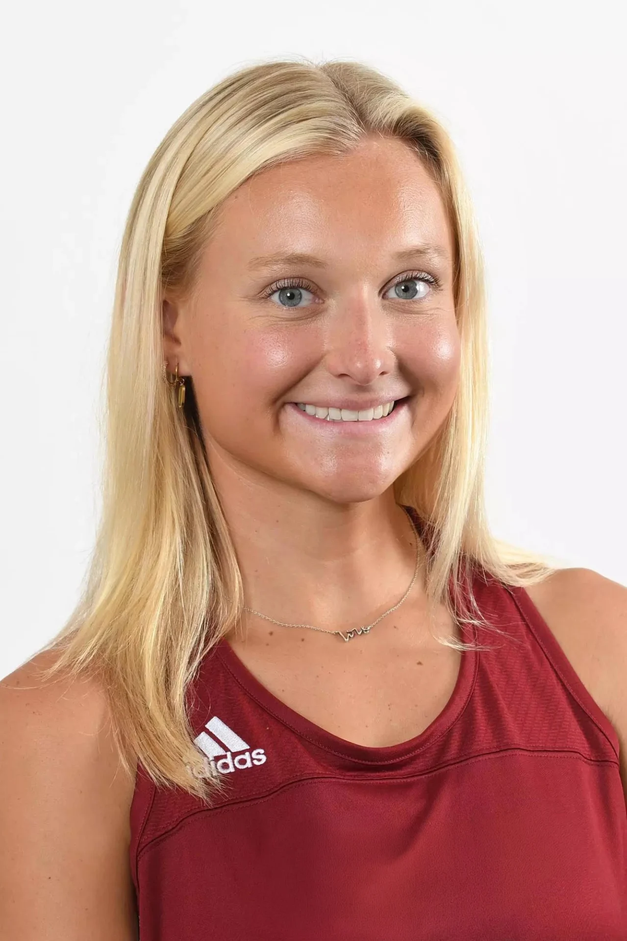Smiling young woman with blond hair, wearing a red athletic shirt.